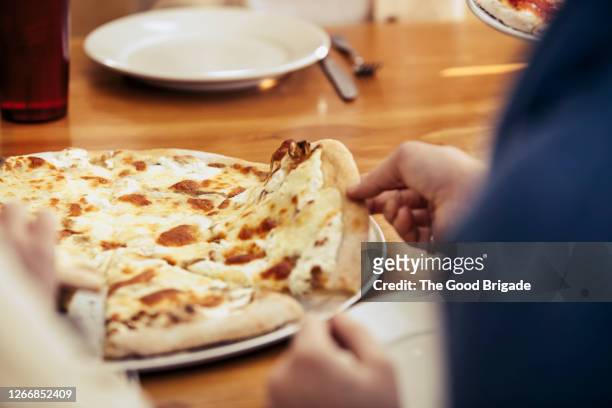 close up of woman grabbing a slice of pizza - vit pizza bildbanksfoton och bilder