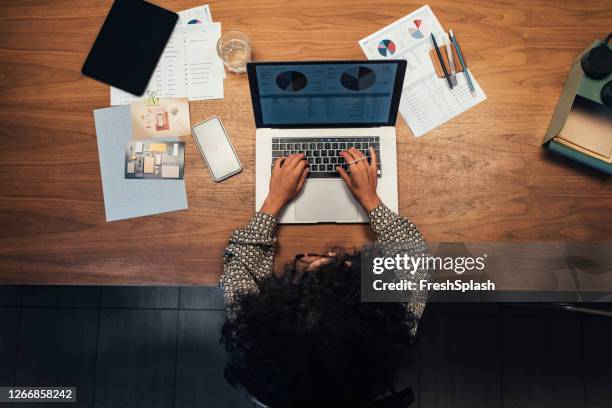 anonyme geschäftsfrau analysiert statistische geschäftsberichte auf ihrem laptop-pc im büro, eine overhead-ansicht - splash news stock-fotos und bilder