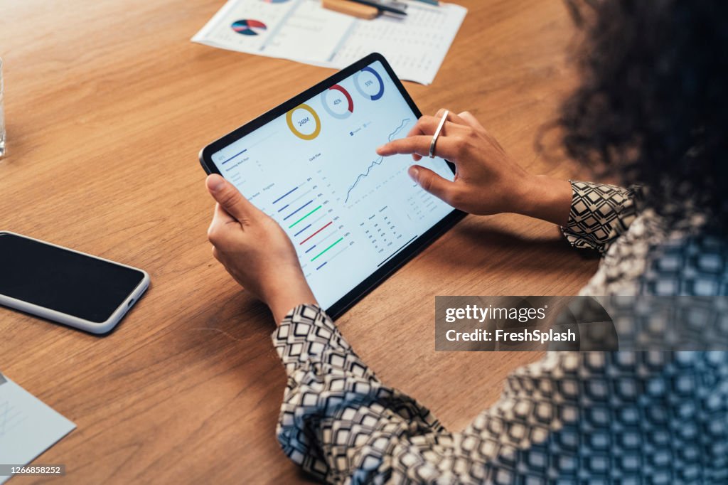 Donna d'affari anonima che analizza i report aziendali statistici sul suo Tablet PC in Ufficio, un primo piano