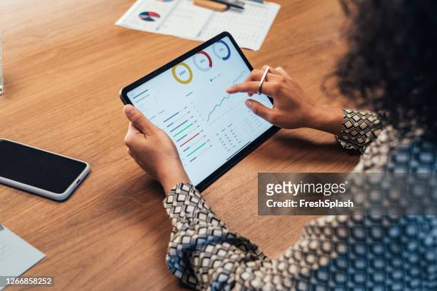 donna d'affari anonima che analizza i report aziendali statistici sul suo tablet pc in ufficio, un primo piano - guardare in una direzione foto e immagini stock