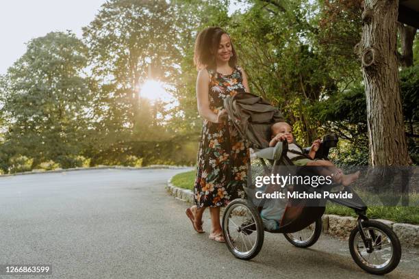 black mom pushing a baby stroller outdoors during summer - baby stroller imagens e fotografias de stock