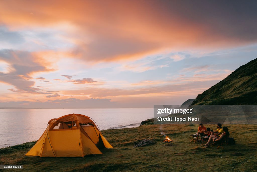 Family camping by the sea at sunset