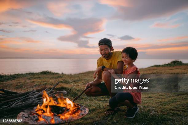 father and daughter enjoying campfire at campsite at sunset - campfire fotografías e imágenes de stock