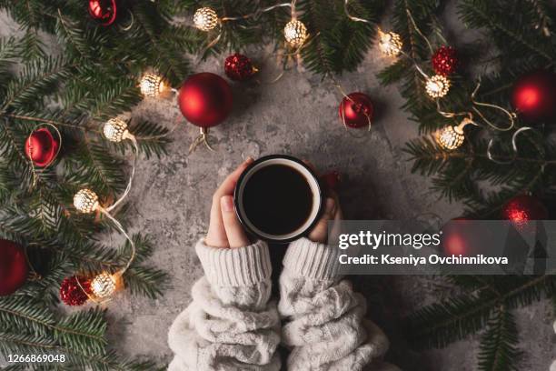 female hand holding cup of hot cocoa or chocolate with marshmallow on wooden table from above - chocolate top view stock-fotos und bilder