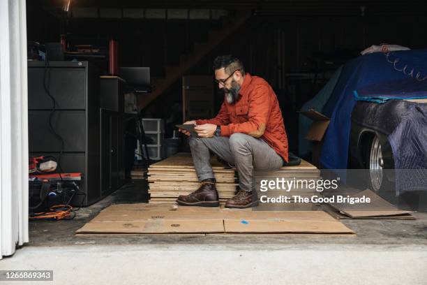 Mature man looking at digital tablet while sitting in garage