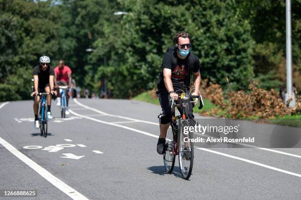 Man wearing a mask rides a bicycle in Prospect Park as the city continues Phase 4 of re-opening following restrictions imposed to slow the spread of...
