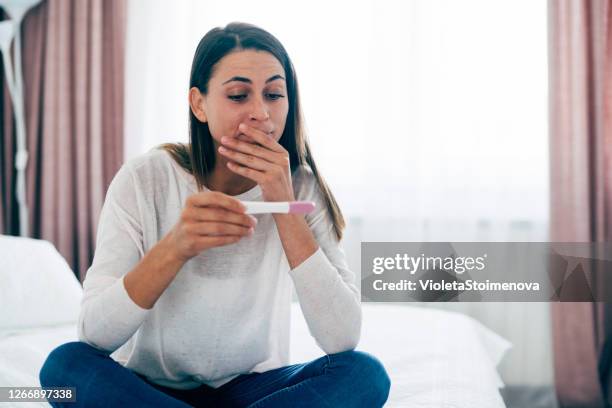 young woman with pregnancy test at home - ovulation stock pictures, royalty-free photos & images