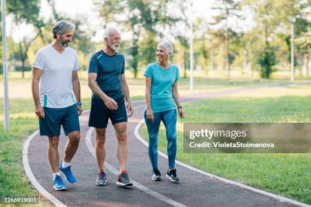 smiling senior athletes jogging in the park - 3 old men jogging stock pictures, royalty-free photos & images