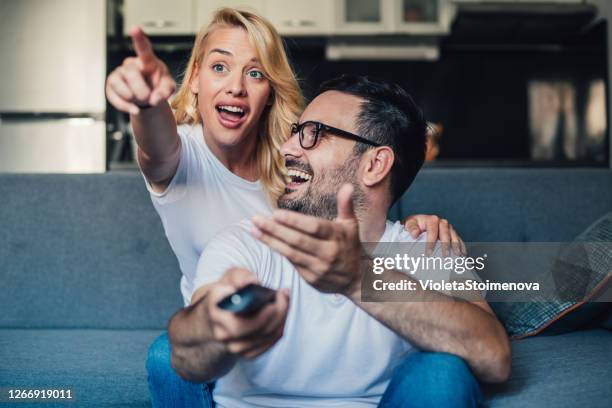 cute young couple cuddling while watching tv. - young couple watching tv stock pictures, royalty-free photos & images