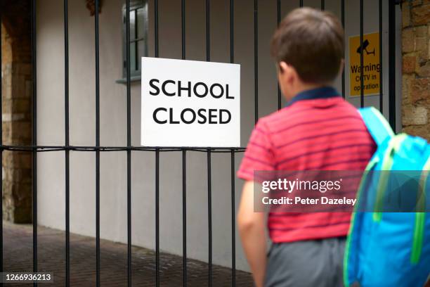 school closed, disappointed boy arriving at school gates - school gates stock-fotos und bilder