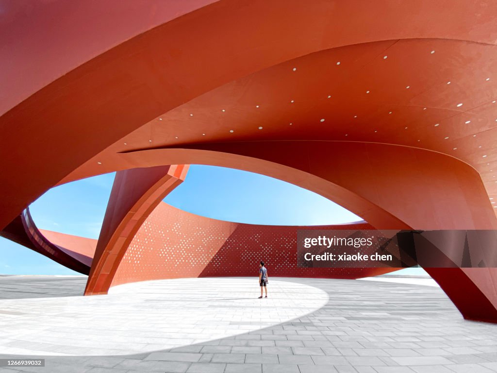 Una persona in uno spazio architettonico astratto curvo rosso, rendering 3D