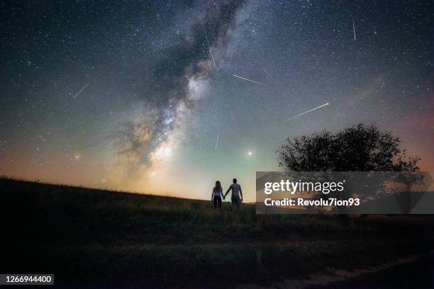 junges paar beobachtet den perseiden-meteorschauer und die milchstraße - astronomie stock-fotos und bilder