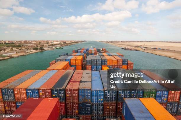 Loaded containers stacked on top of a cargo ship sailing in a canal on Janvier 20, 2017 in Suez Canal, Red sea, Egypt.