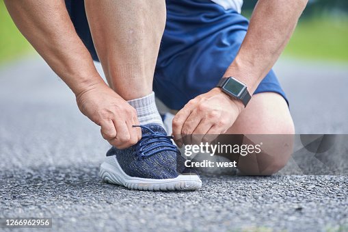 Hand of senior man tying shoelaces Hand of senior man tying shoelaces