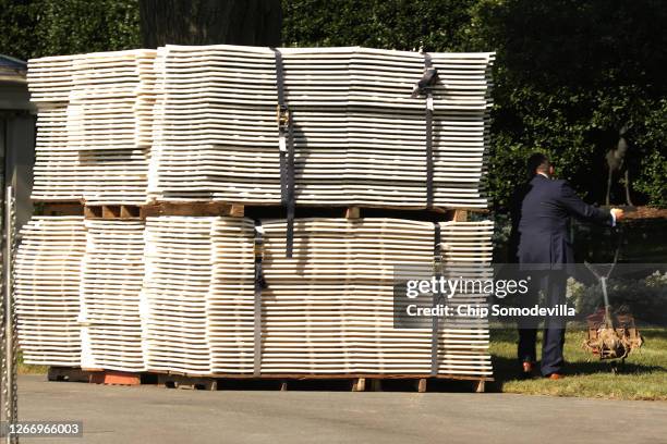 Secret Service agent moves a garden tiller past a stack of temporary flooring on the South Lawn before President Donald Trump departs the White House...