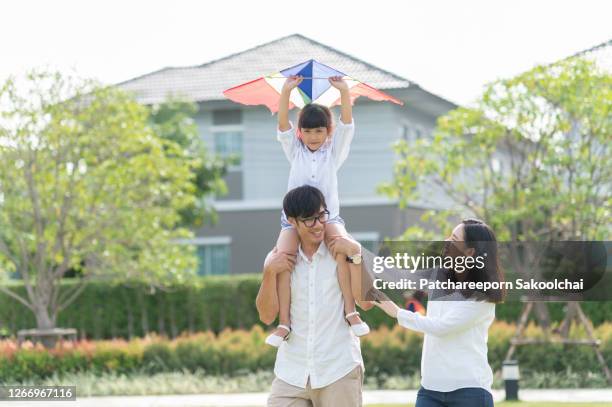 family having fun in front yard of house - thailand kite stock-fotos und bilder