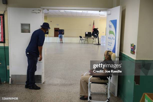 Poll workers look on as a voter fills out his ballot on primary election day on August 18, 2020 in Miami, Florida. Voters are casting ballots in...