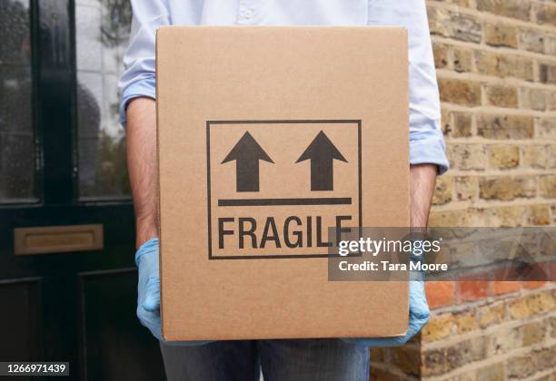 man holding cardboard box with protective gloves - consegna a domicilio foto e immagini stock