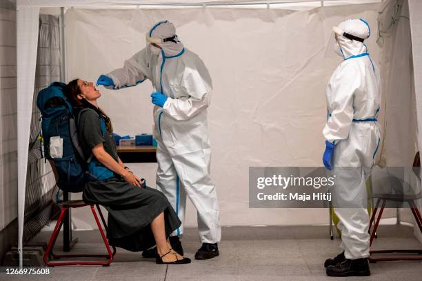 Member of the German Red Cross wears a PPE protective suit while taking a throat swab sample from a person at a Covid-19 testing station set up at...