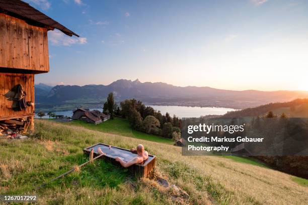 man in the swiss mountain taking a dip in the cattle trough at sunset - whirlpool stock-fotos und bilder