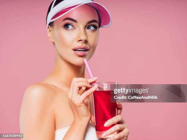 beautiful girl with cherry juice on a pink background - red drink stock pictures, royalty-free photos & images