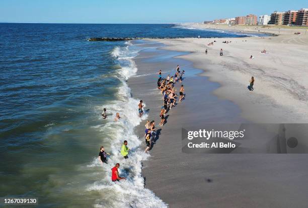 An aerial view of members of the Jetty Fitness Club train in the ocean with what they call a "Life Outside the Box" workout led by fitness instructor...