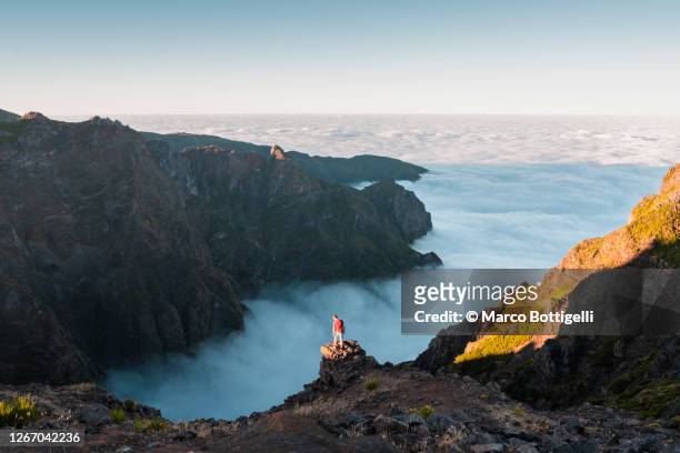 man looking at sea of fog from top of a mountain, madeira, portugal - pico do arieiro fotografías e imágenes de stock