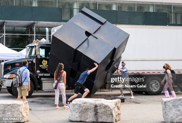 People wear face masks while spinning the Alamo sculpture in Astor Place as the city continues Phase 4 of re-opening following restrictions imposed...