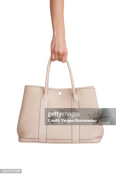 beige leather handbag in woman's hand isolated on white background - cremefarbige handtasche stock-fotos und bilder