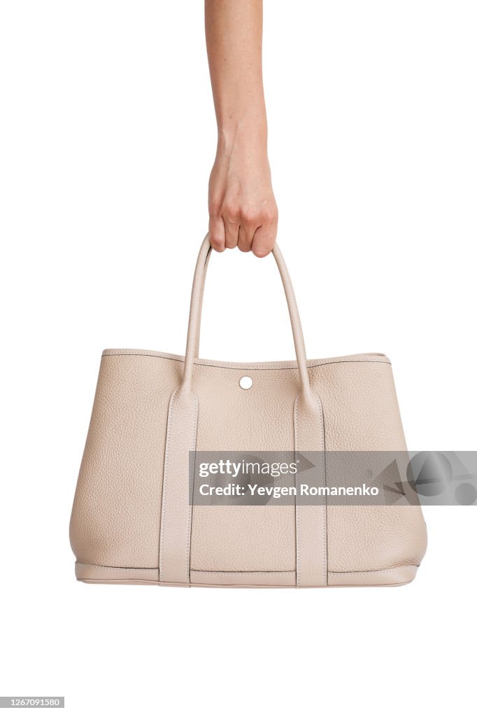 Beige Leather handbag in woman's hand isolated on white background