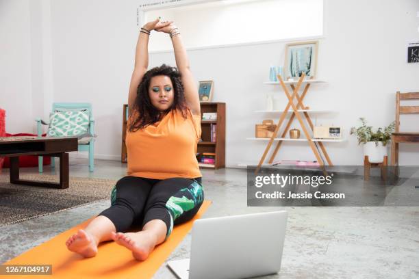 a woman does yoga in her apartment/studio - online yoga stock pictures, royalty-free photos & images