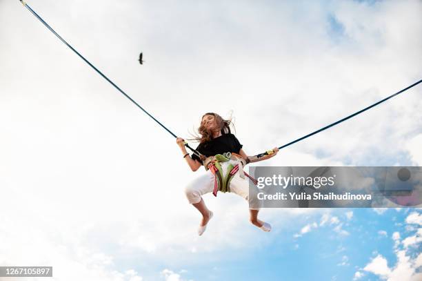 a girl is jumping flying on bungee trampoline - bunjee jumping stock-fotos und bilder