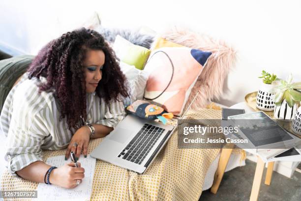 a woman lies on a bed working on her laptop - plus size fashion stock pictures, royalty-free photos & images