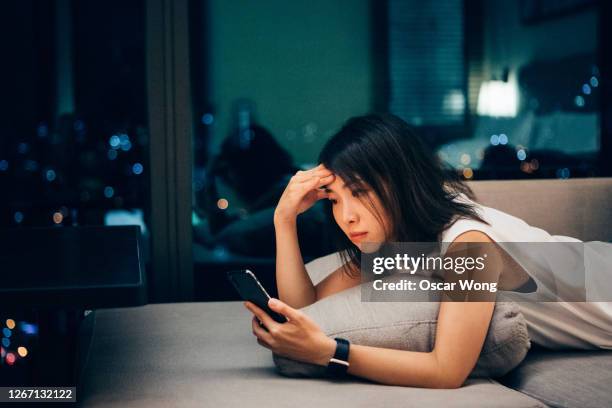 young woman working late and checking work email on mobile at home - centre piece photos et images de collection