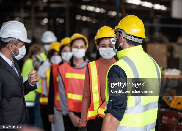 factory manager and staff checking fever digital thermometer for industrial workers before working inside factory to prevent coronavirus infection. - veiligheidsartikelen stockfoto's en -beelden