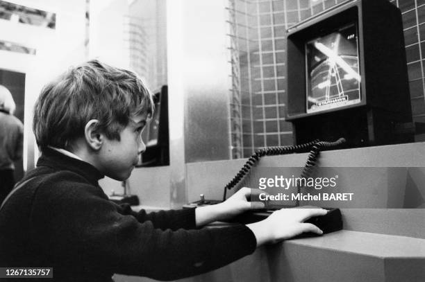 Enfant jouant avec une console de jeux au salon du Jouet, dans le parc des Expositions de Paris, en janvier 1983, France.