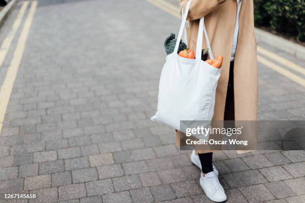 responsible shopper using reusable shopping bag for groceries - herbruikbare tas stockfoto's en -beelden