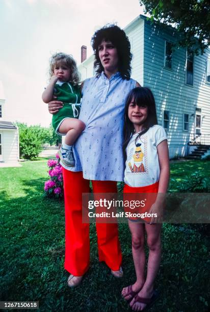 Portrait of Catharene Jurgill and her two daughters as they stand outside their house, Centralia, Pennsylvania, July 1992. Like many homes in the...