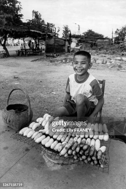 Enfant vendant des bananes grillées dans la rue à Vientiane, en 1988, Laos.