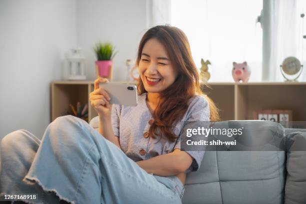 woman watch on cellphone at home - smartphone video stock pictures, royalty-free photos & images
