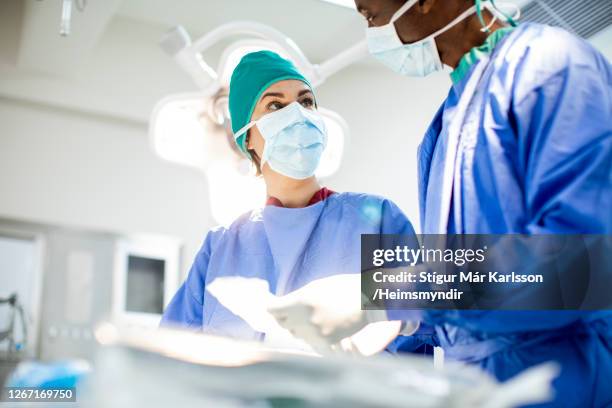 two diverse doctors prepping for an operation in a hospital - critical care stock pictures, royalty-free photos & images