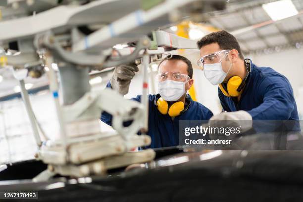 mechanics fixing a helicopter while wearing a facemasks - blue collar worker mask stock pictures, royalty-free photos & images