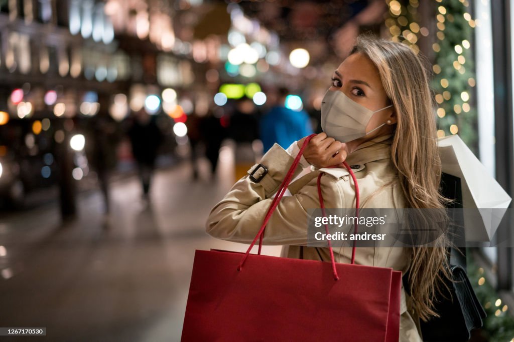 Feliz mujer de compras de Navidad con una máscara facial