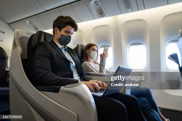 personen, die mit dem flugzeug in der business class reisen und gesichtsmasken im flugzeug tragen - air respirator mask stock-fotos und bilder