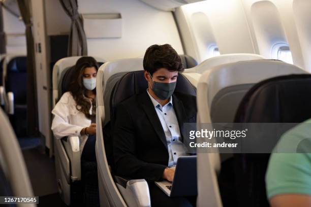 business man traveling and wearing a facemask on the plane - covid-19 air travel stock pictures, royalty-free photos & images