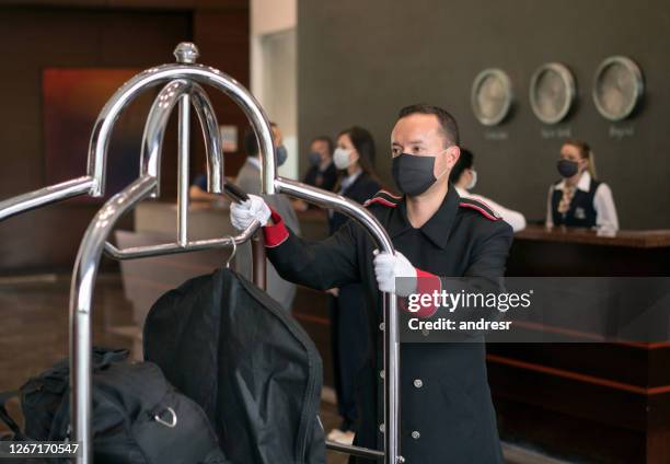 loopjongen die bij een hotel werkt dat een facemask draagt - portier stockfoto's en -beelden