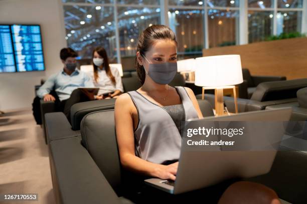 traveling business woman wearing a facemask at the airport and working online at the vip lounge - businesswoman mask stock pictures, royalty-free photos & images