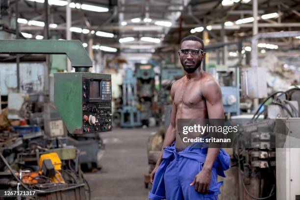 african american factory worker or technician show upper muscular body by take of suit and look to camera - close up body part stock pictures, royalty-free photos & images