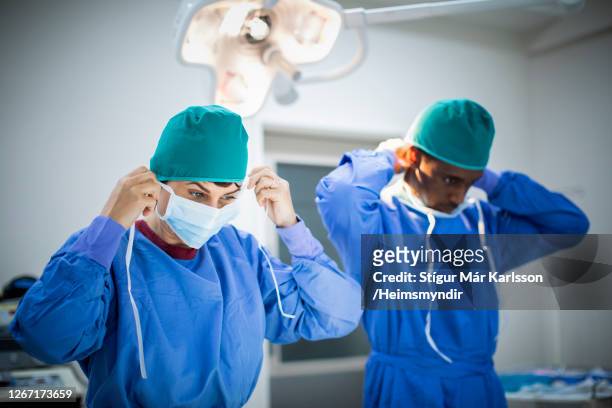 two doctors prepping for an operation in an operating room - determination doctor stock pictures, royalty-free photos & images