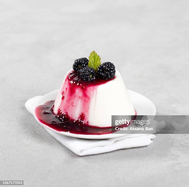 italian cream dessert panna cotta with berry sauce and blackberries on a plate on a light background - panna cotta photos et images de collection